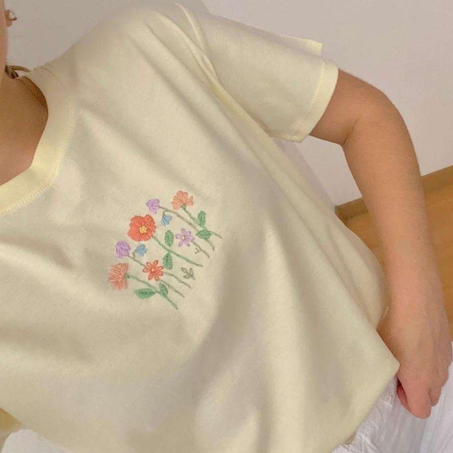 The embroidered T-shirt stands out for its tactile richness and artisanal feel.
